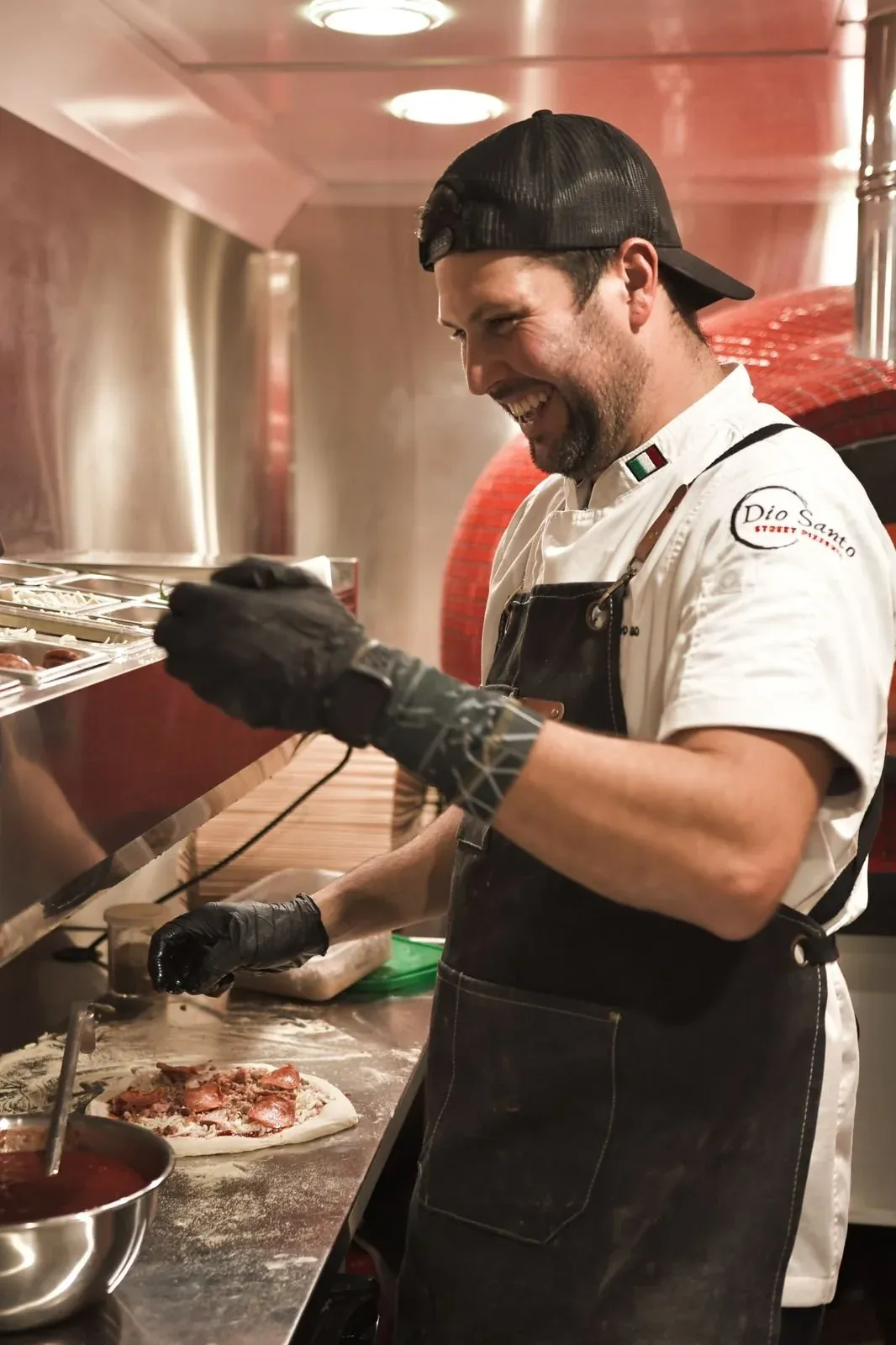 Chef Gustavo Leão preparing a pizza inside the Dio Santo food truck
